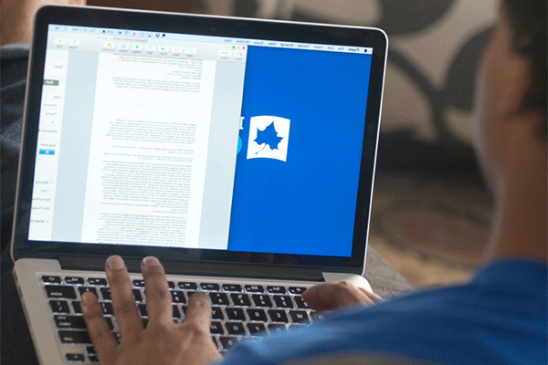 An over the shoulder image of a black male student using a laptop, with an Indiana State University page showing on the screen